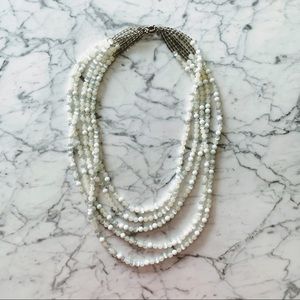 Long white multi-strand bead necklace.